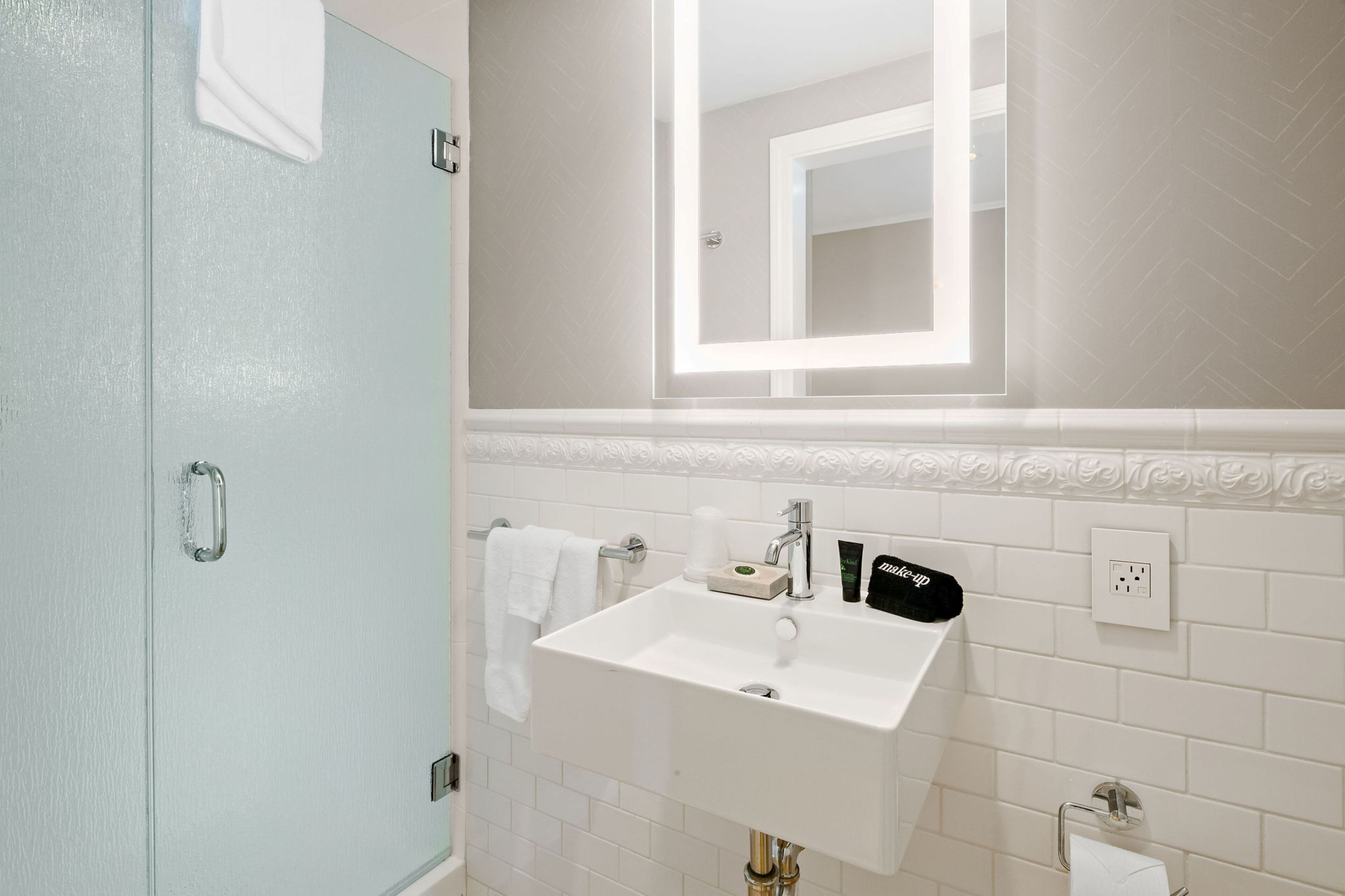A bathroom with a white sink, mirror, and towel rack.