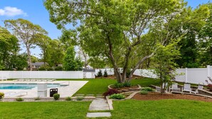 A backyard with a swimming pool, a stone pathway, and a white fence. - Love Farms Lodge (West Dennis)