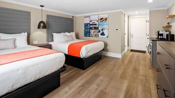 Une chambre d’hôtel avec deux lits, une kitchenette et une porte donnant sur une autre pièce.