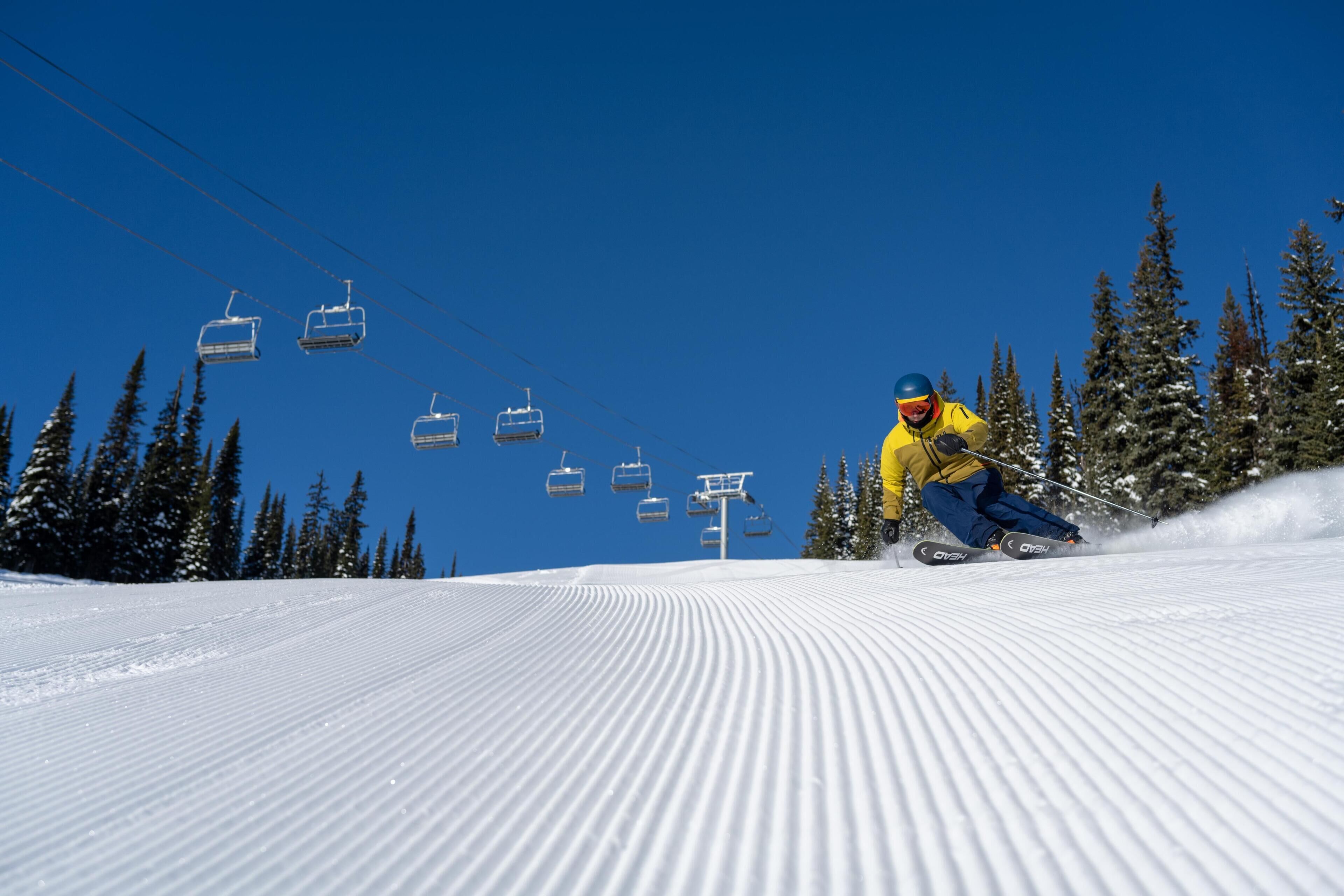 A ski slope with a person skiing and a ski lift in the background.