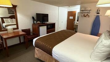 Une chambre d’hôtel équipée d’un lit, d’un bureau, d’une télévision, d’un four à micro-ondes et d’un espace douche.