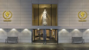 A building entrance with a statue, two benches, and a logo on the wall. - Caesars Windsor Hotel & Casino - A Caesars Rewards Destination (Windsor)