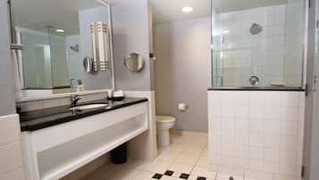 A modern bathroom with a black countertop sink, a large mirror, a toilet, and a glass-enclosed shower area.
