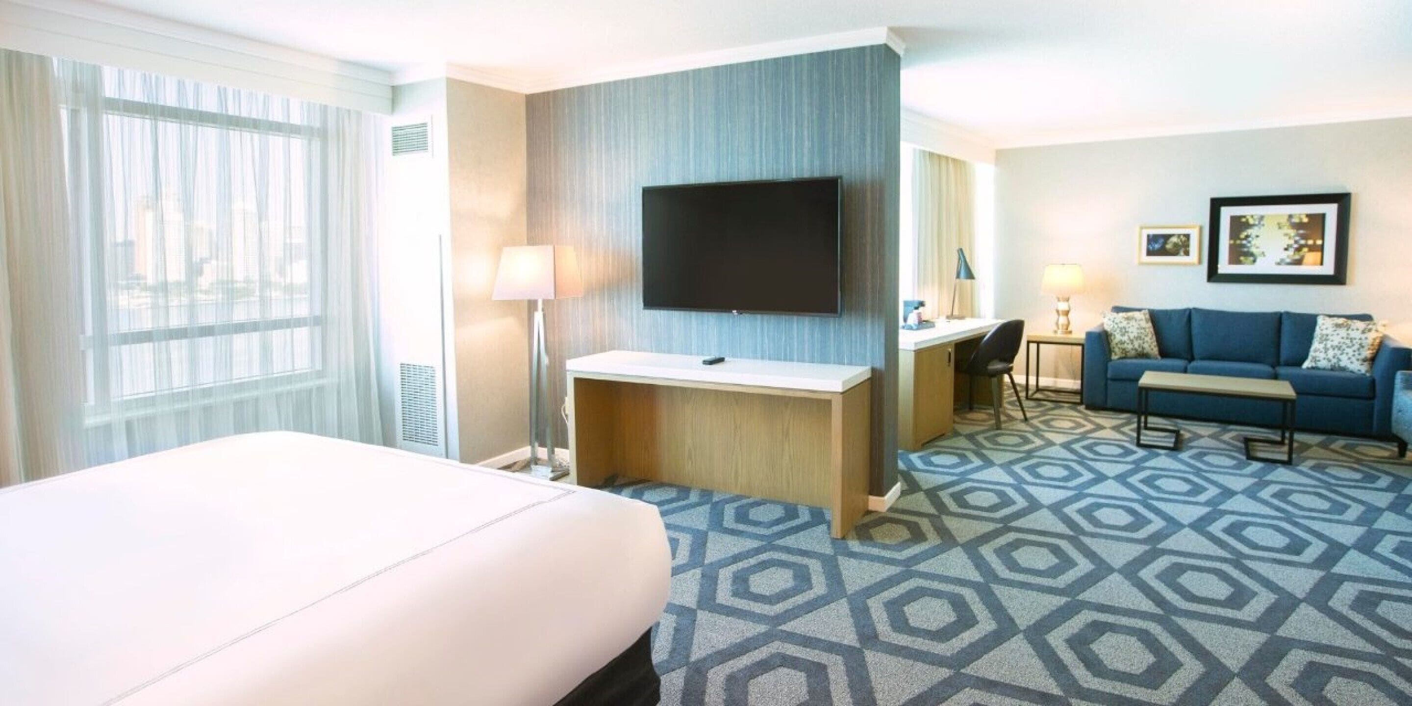 Een hotelkamer met een bed, bureau, televisie en een bank.