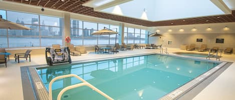 An indoor swimming pool with clear views of a city skyline through large windows.