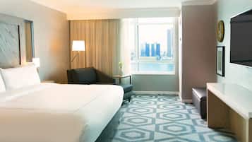 Een hotelkamer met een groot bed, een bureau, een stoel, een lamp en een televisie.