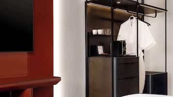 Une chambre d’hôtel moderne équipée d’un lit, d’une télévision, d’une armoire et d’un petit bureau avec une chaise.