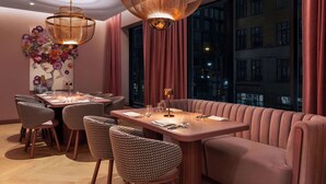 Un comedor moderno con una mesa redonda, asientos acolchados e iluminación colgante.