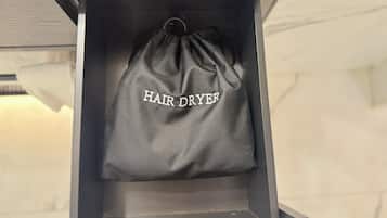 A black drawstring bag with "HAIR DRYER" written on it hanging in a cabinet.