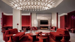 A modern lounge area with a fireplace, red seating, and a unique ceiling light fixture. - Revery Toronto Downtown, Curio Collection by Hilton (Toronto)