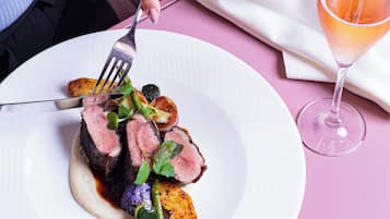 A plate of food with a fork and a glass of drink on a table.