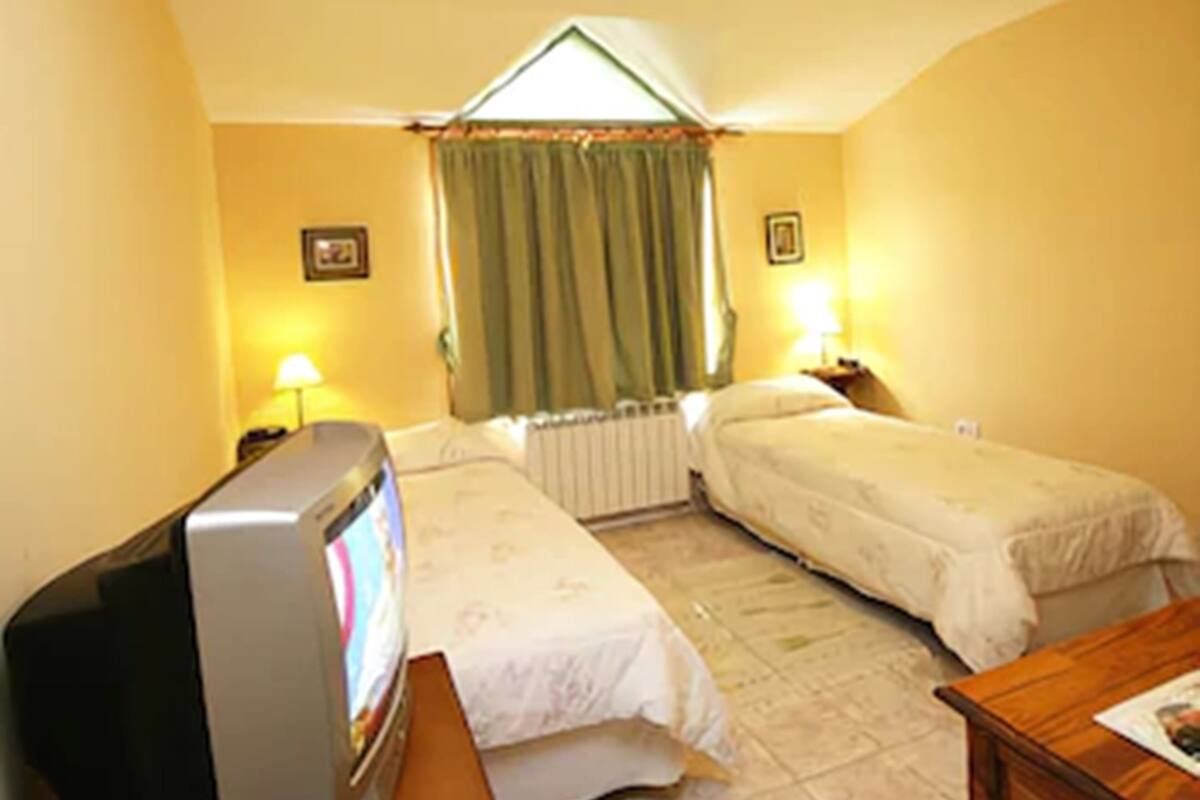 Una habitación con dos camas, televisión y una mesita.