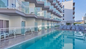 A modern hotel with a swimming pool, multiple balconies, and outdoor seating areas.