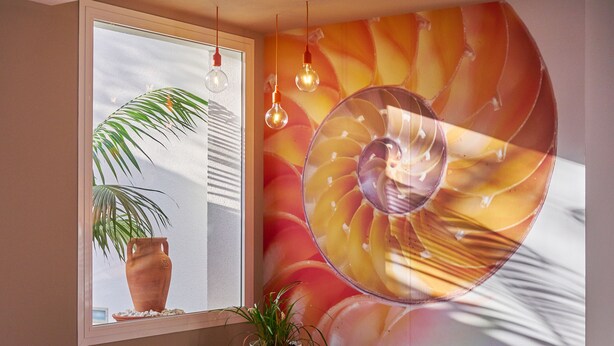 A modern room with a large window, a round wall decoration, and a seating area.
