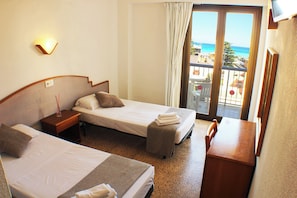 A hotel room with two beds, a desk, and a balcony with a view of the sea. - Villa Barbara (Santa Margalida)