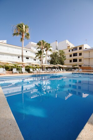 Una piscina al aire libre, sombrillas, tumbonas