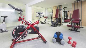 Un gimnasio con equipo de ejercicio, incluyendo una bicicleta estática, máquinas de pesas y mancuernas.