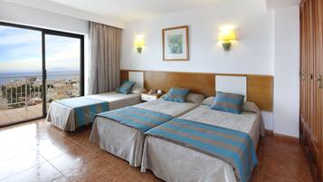 Habitación de hotel con dos camas, un balcón y vista a la ciudad, además de un cuadro en la pared.