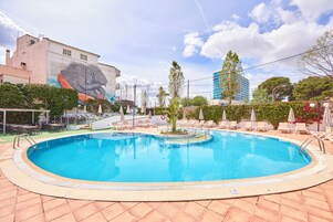 A swimming pool with lounge chairs and a mural on the adjacent building.
