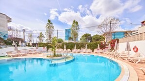 A swimming pool with lounge chairs and umbrellas, surrounded by greenery and buildings. - Ilusion Markus & Spa (Santa Margalida)