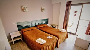 A hotel room with two beds, a painting on the wall, a small table, and a view of the outside. - Raxa (Palma de Mallorca)