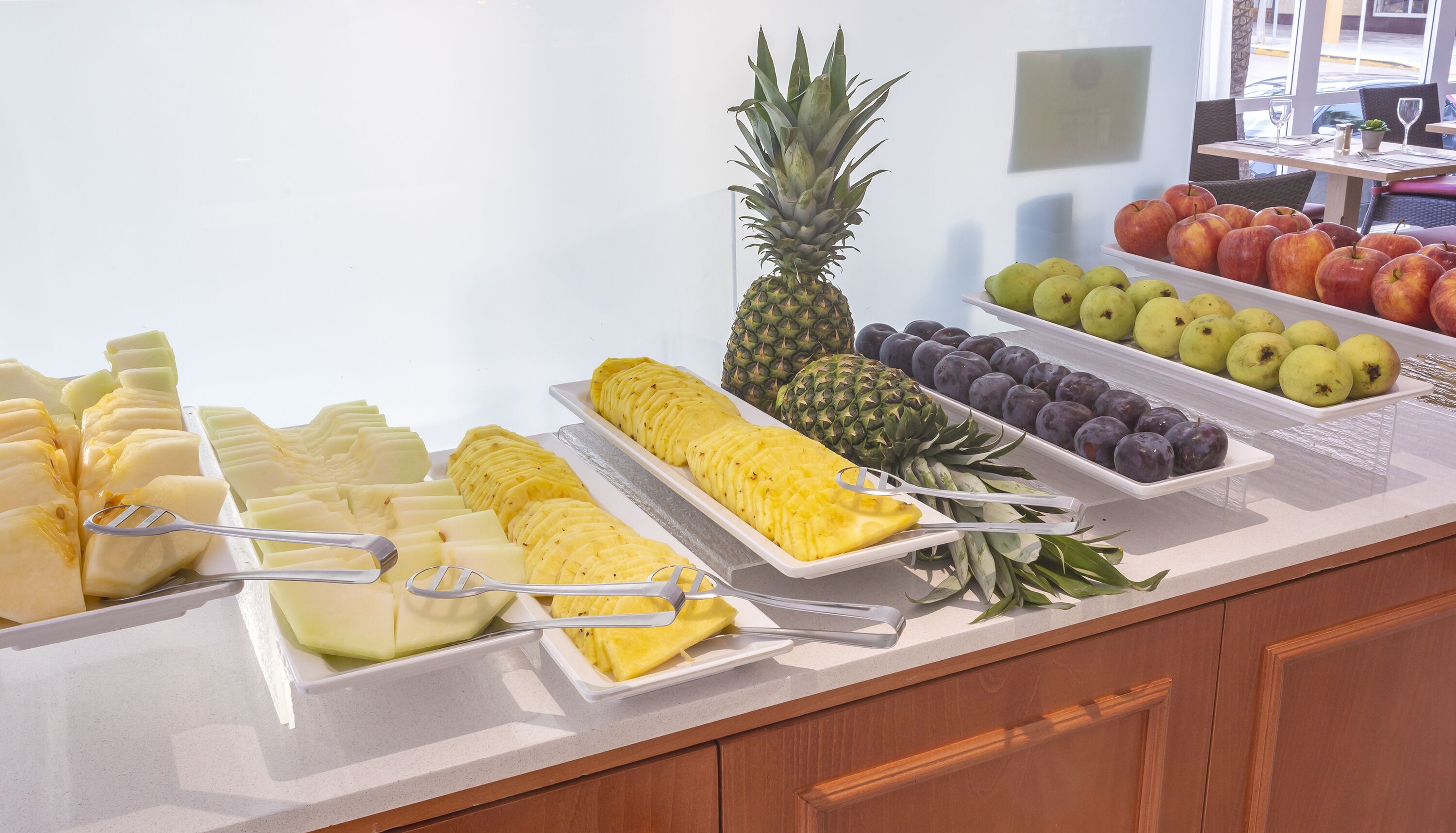 A buffet with various fruits and vegetables, including pineapple, apples, and pears.