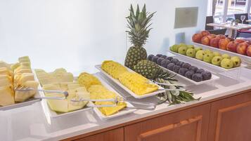 A buffet with various fruits and vegetables, including pineapple, apples, and pears.