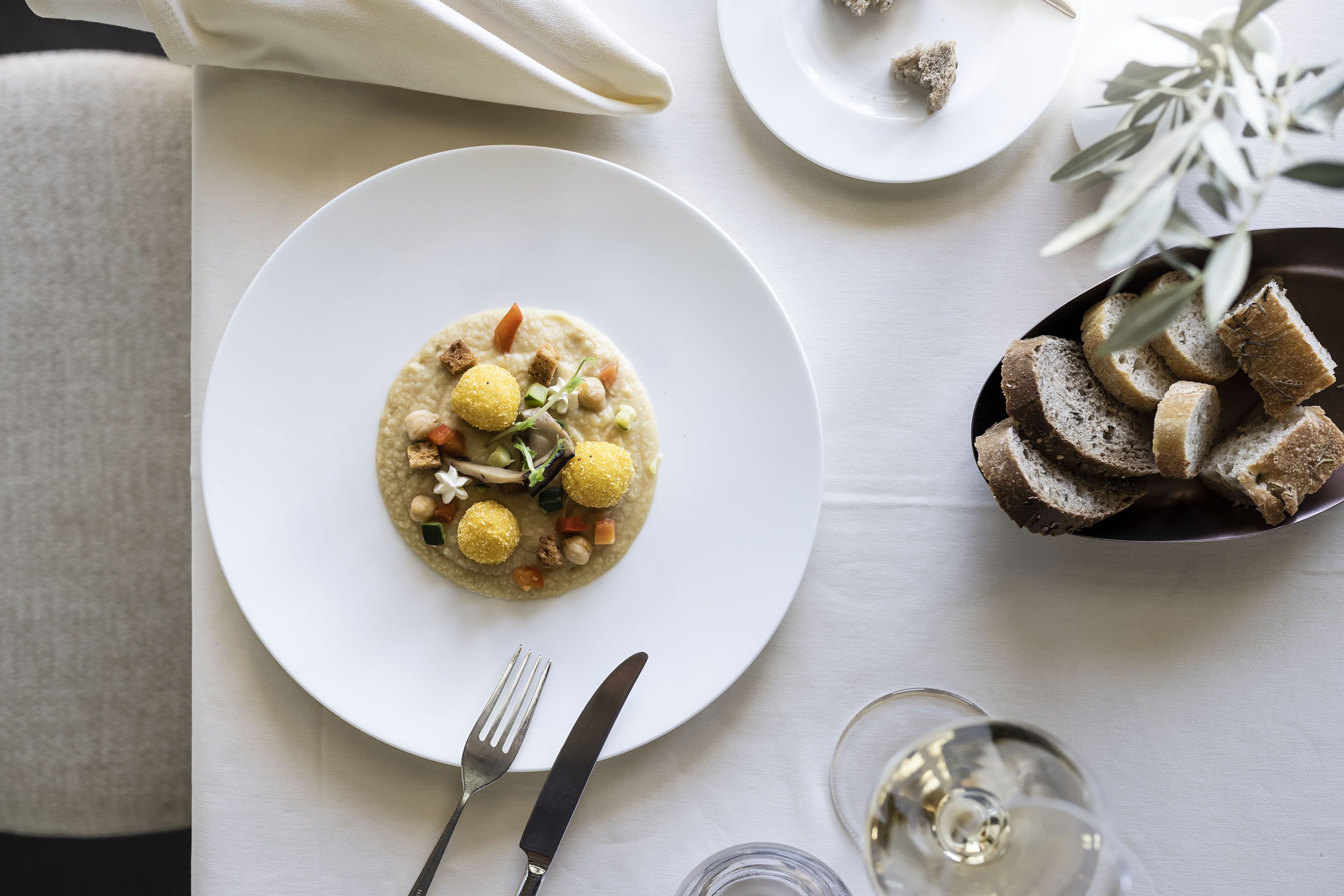 A dining table with a plate of food, cutlery, and a glass of water.