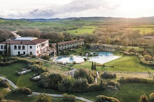 A large hotel with multiple buildings, a swimming pool, and a well-maintained garden.
