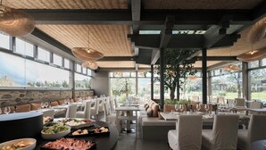 Un restaurante con área de bar, mesas y sillas, y vistas al exterior.