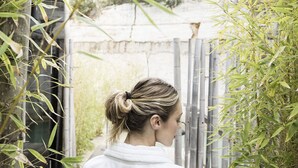 Una persona vestida con una bata blanca en un jardín de bambú.