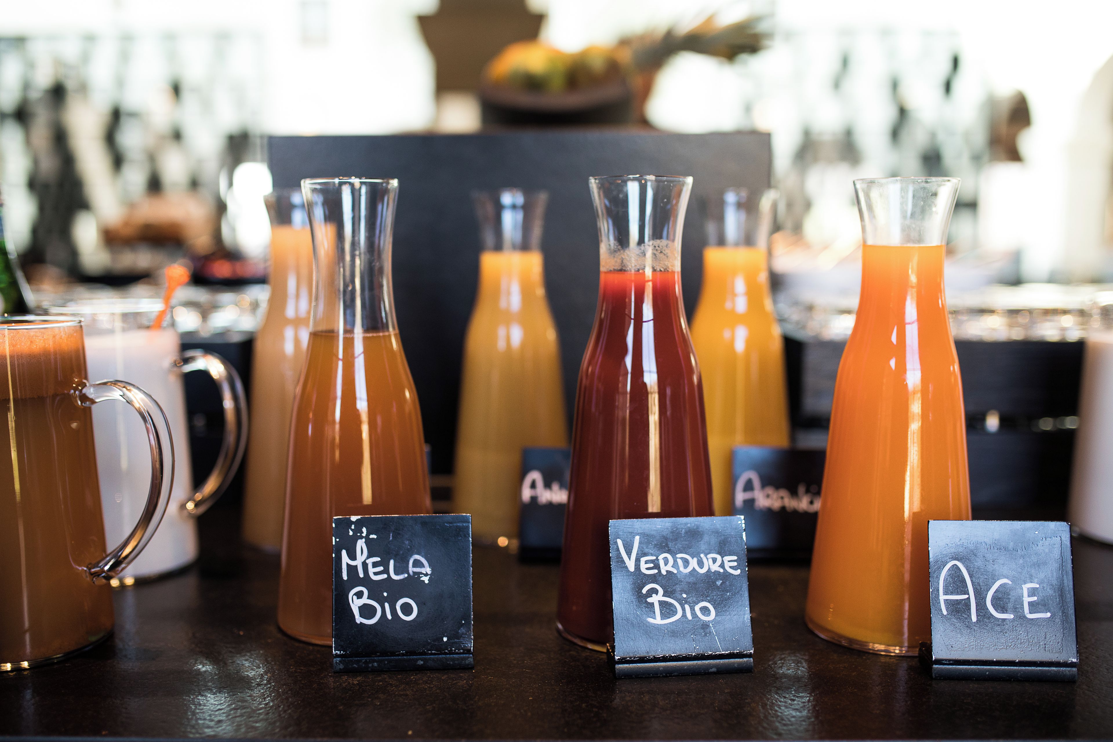 Une variété de boissons proposées dans des bouteilles en verre, dont les étiquettes indiquent les saveurs, par exemple « Hello Bio », « Verdure Bio » et « Ace ».