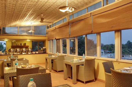 A dining area with wicker furniture, large windows, and a ceiling with a geometric pattern.