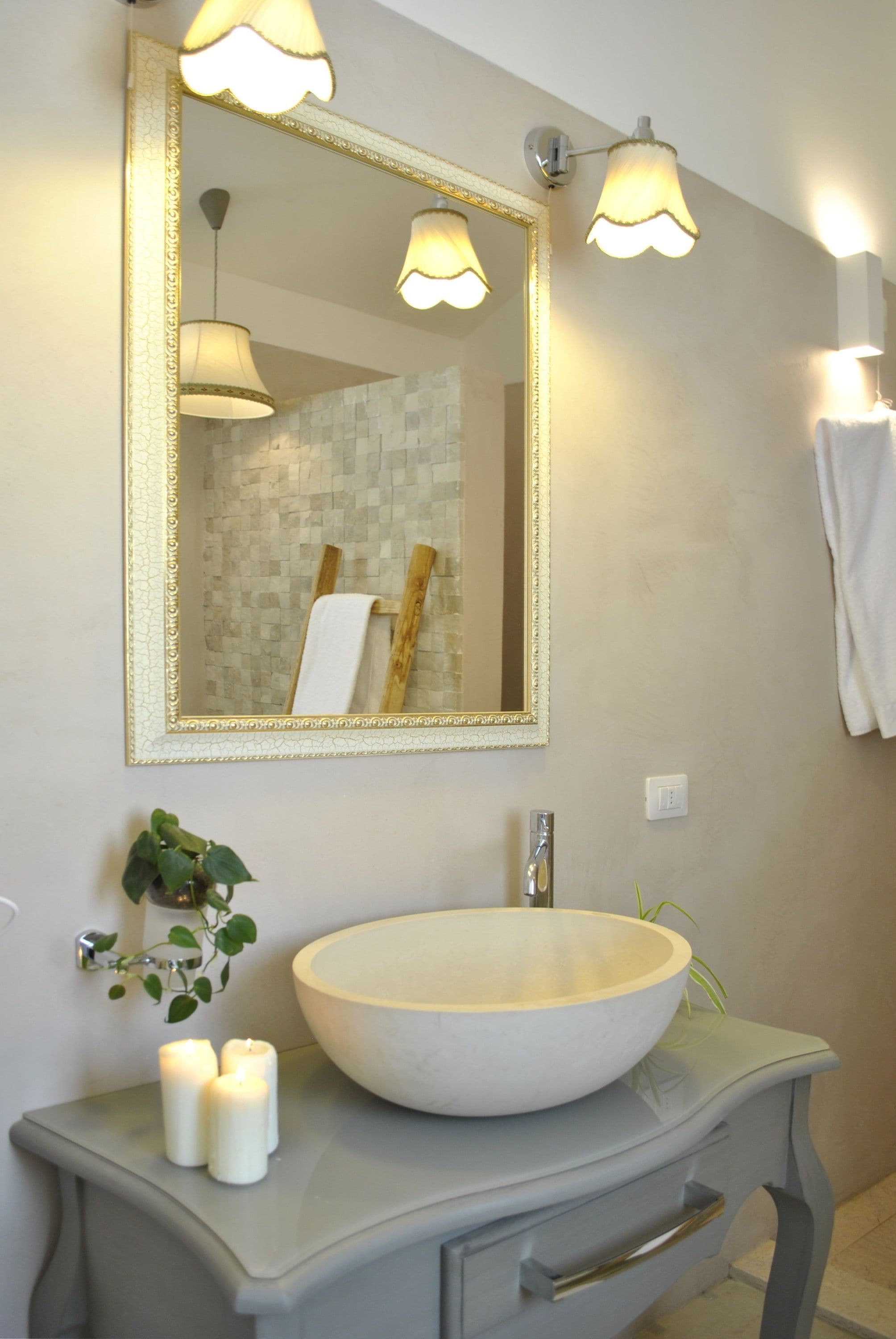 A bathroom with a large mirror, a vessel sink, and wall-mounted lights.