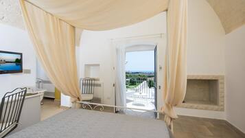 Un dormitorio con cama, televisión, baño y balcón con vistas.