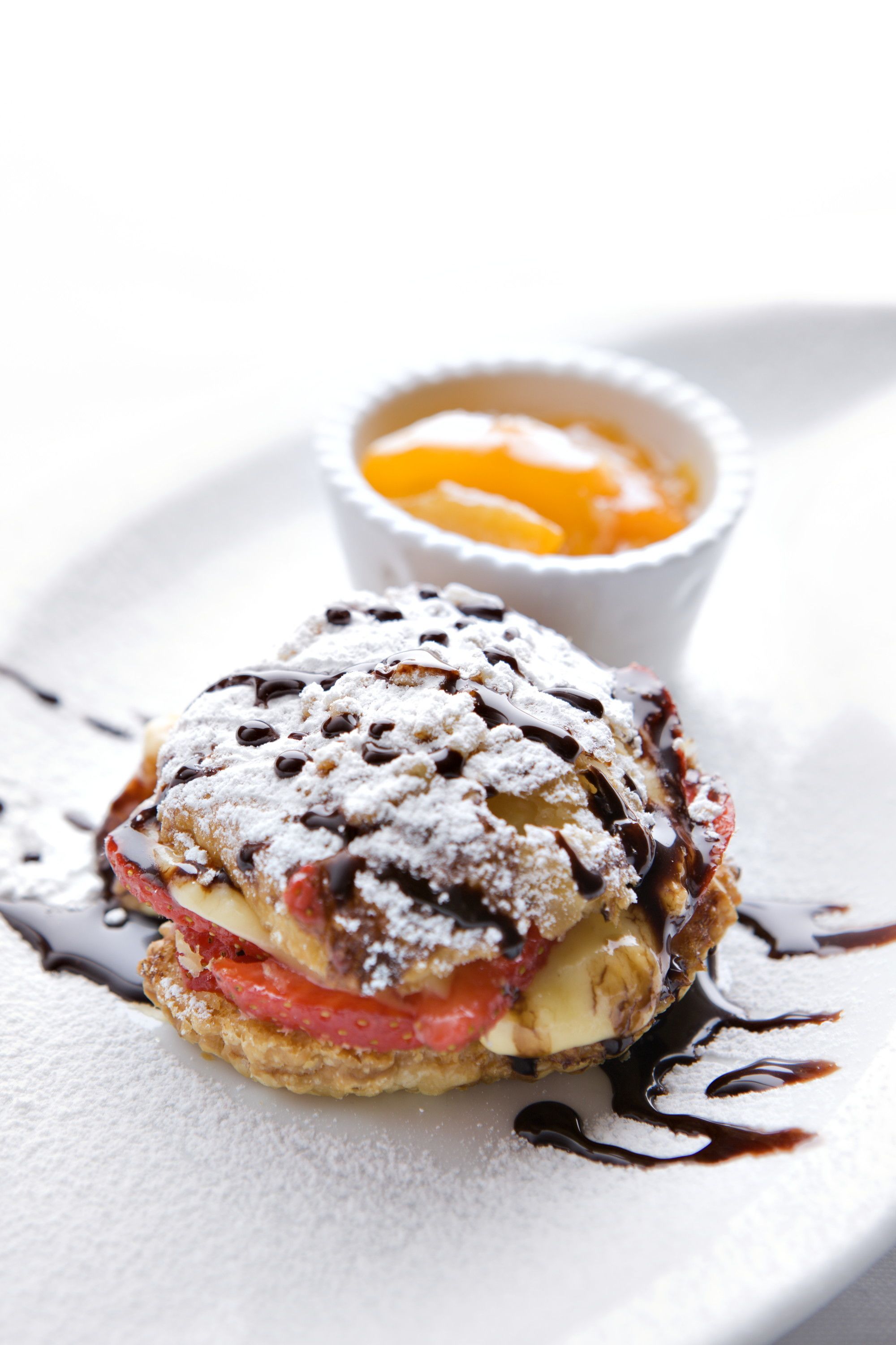 A dessert with powdered sugar and chocolate drizzle on a plate.