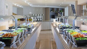 Zona de bufé con múltiples estaciones de comida, un interior limpio y moderno, y un ambiente bien iluminado.
