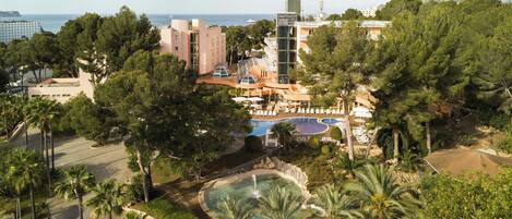 Un resort con piscina, palmeras y vista al mar.
