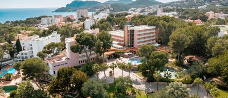 A resort with multiple buildings, a swimming pool, and a view of the sea.