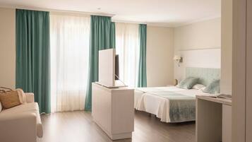 Ein Hotelzimmer mit einem Bett, einem Schreibtisch, einem Stuhl, einem Kleiderschrank und einem Fernseher.