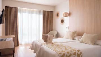 A hotel room with two beds, a desk, and a chair.