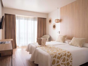 Habitación de hotel con dos camas, un escritorio y una silla.