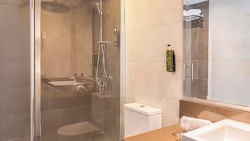 A modern bathroom with a glass-enclosed shower, a toilet, a sink, and a large mirror.