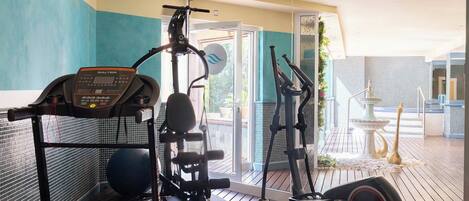 Une salle de sport à domicile équipée d’un tapis de course, d’un vélo elliptique et d’une machine de musculation.