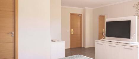 A hotel room with a bed, a television, a wardrobe, and a door.