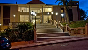 A hotel entrance with a staircase, palm trees, and a car parked nearby. - Hotel Bordoy Don Antonio (Calvia)