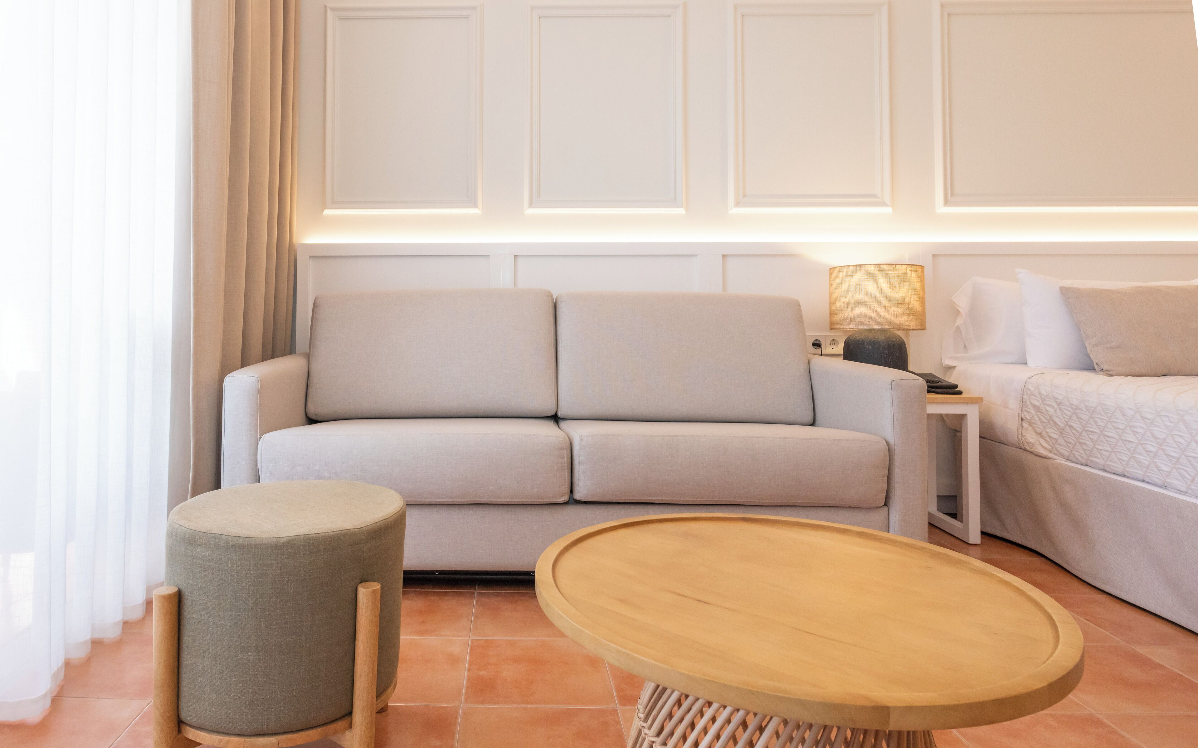 Una sala moderna con un sofá, un reposapiés y una mesa redonda de madera.
