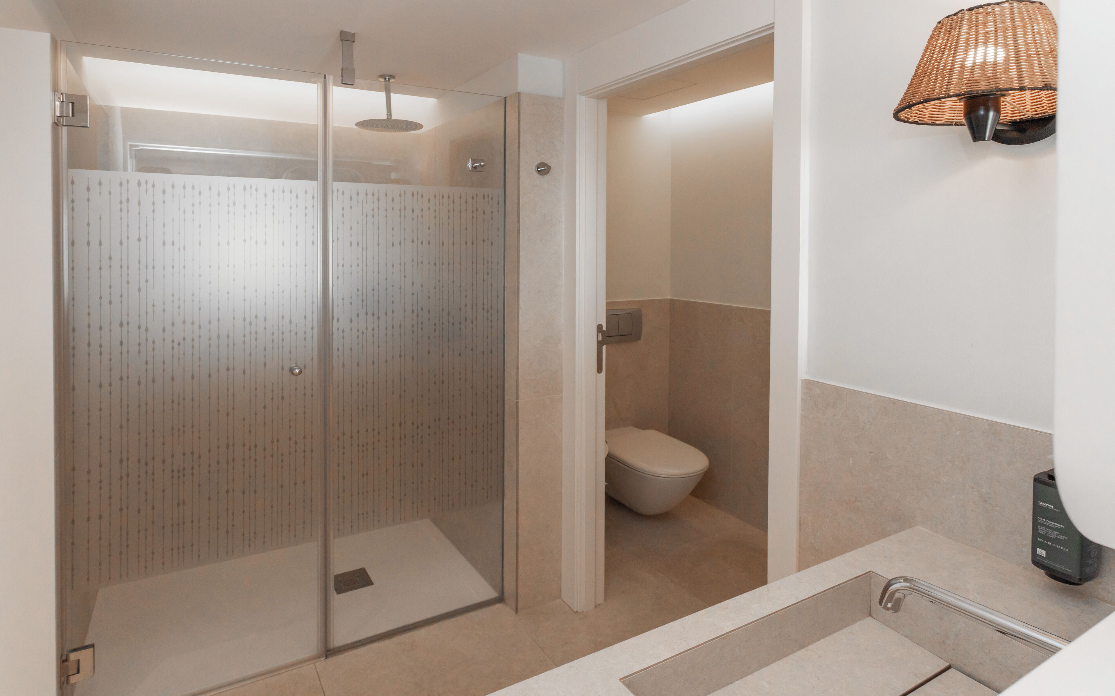 A modern bathroom with a glass-enclosed shower, a toilet, and a sink with a towel rack.
