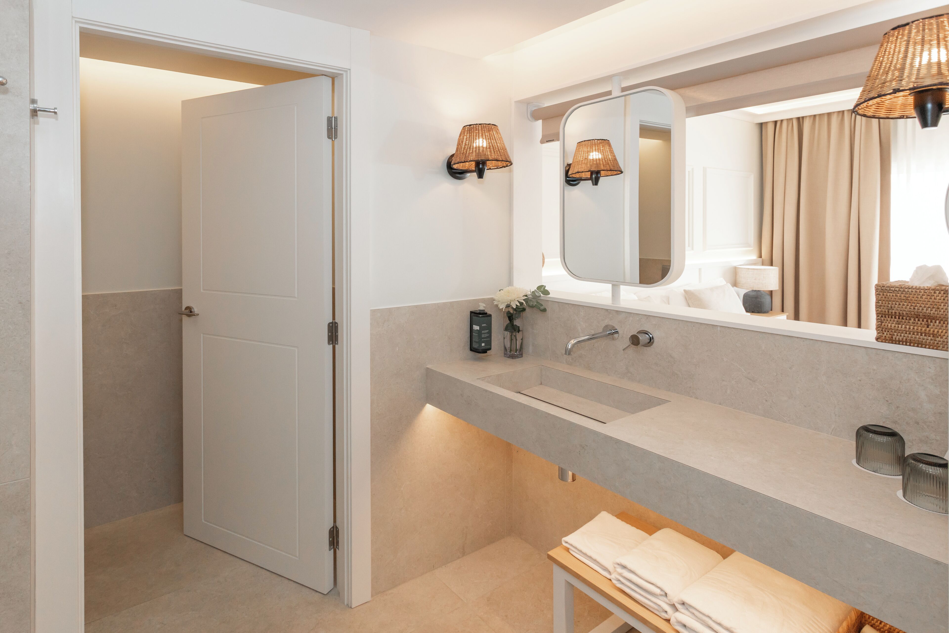 Un baño moderno con un espejo grande, un lavamanos y un banco con toallas.