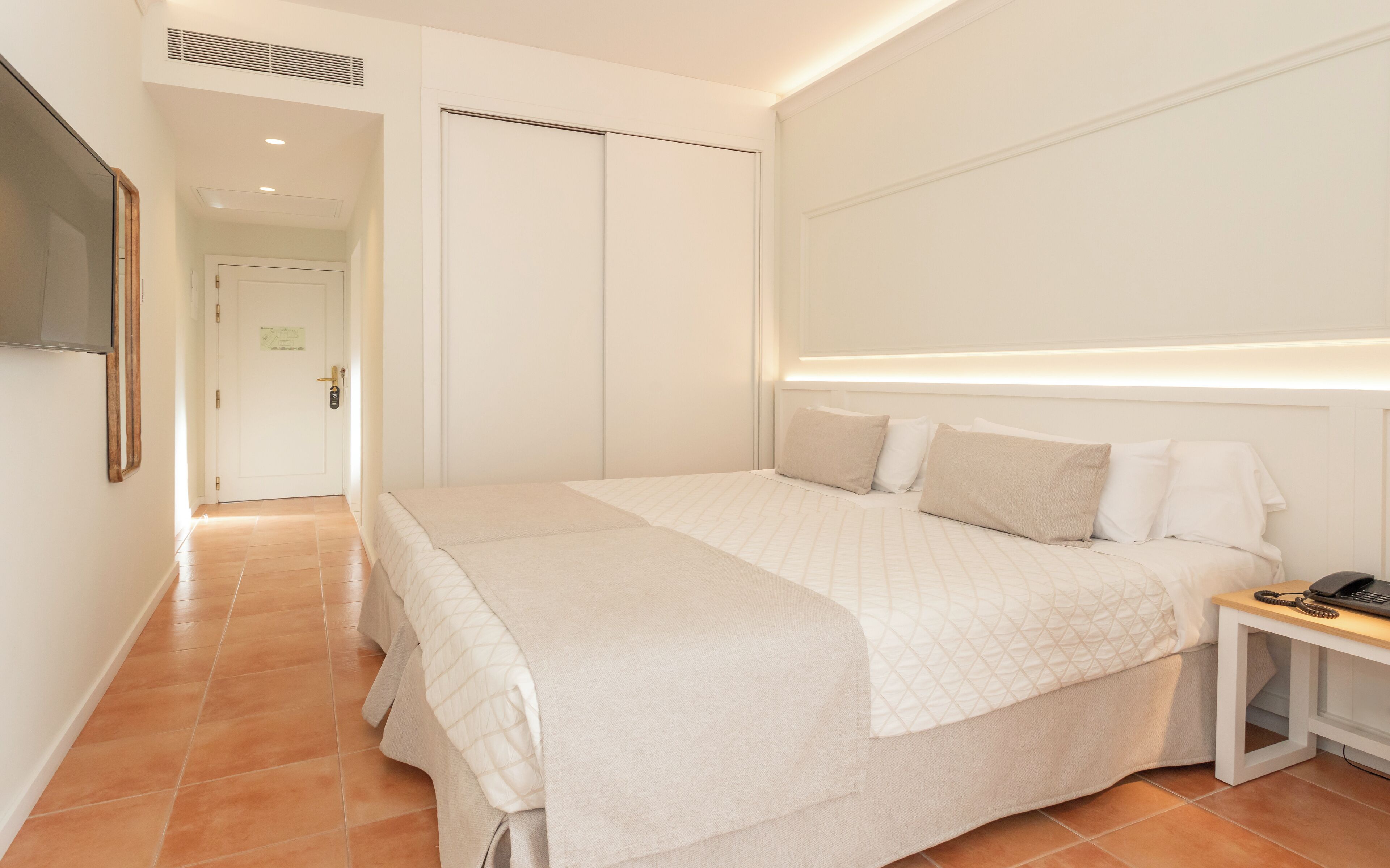 Une chambre à coucher avec un lit, une table de chevet et un téléviseur fixé au mur.